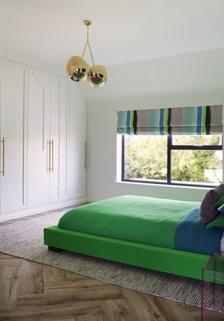 white bedroom with green bed and joinery