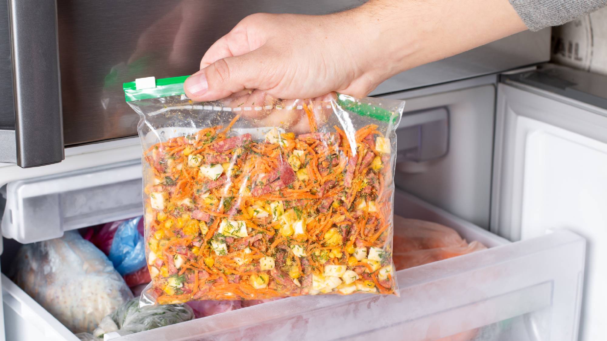 Food scraps in ziplock bag being placed in freezer