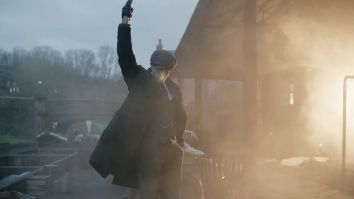 Rambert Dance Company&#039;s Peaky Blinders: The Redemption of Thomas Shelby; a male dancer dressed in a suit and flat cap stands with one arm in the air as if firing a pistol