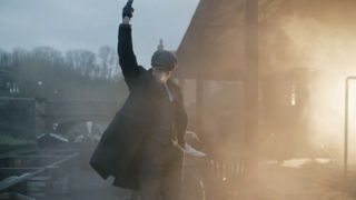 Rambert Dance Company's Peaky Blinders: The Redemption of Thomas Shelby; a male dancer dressed in a suit and flat cap stands with one arm in the air as if firing a pistol