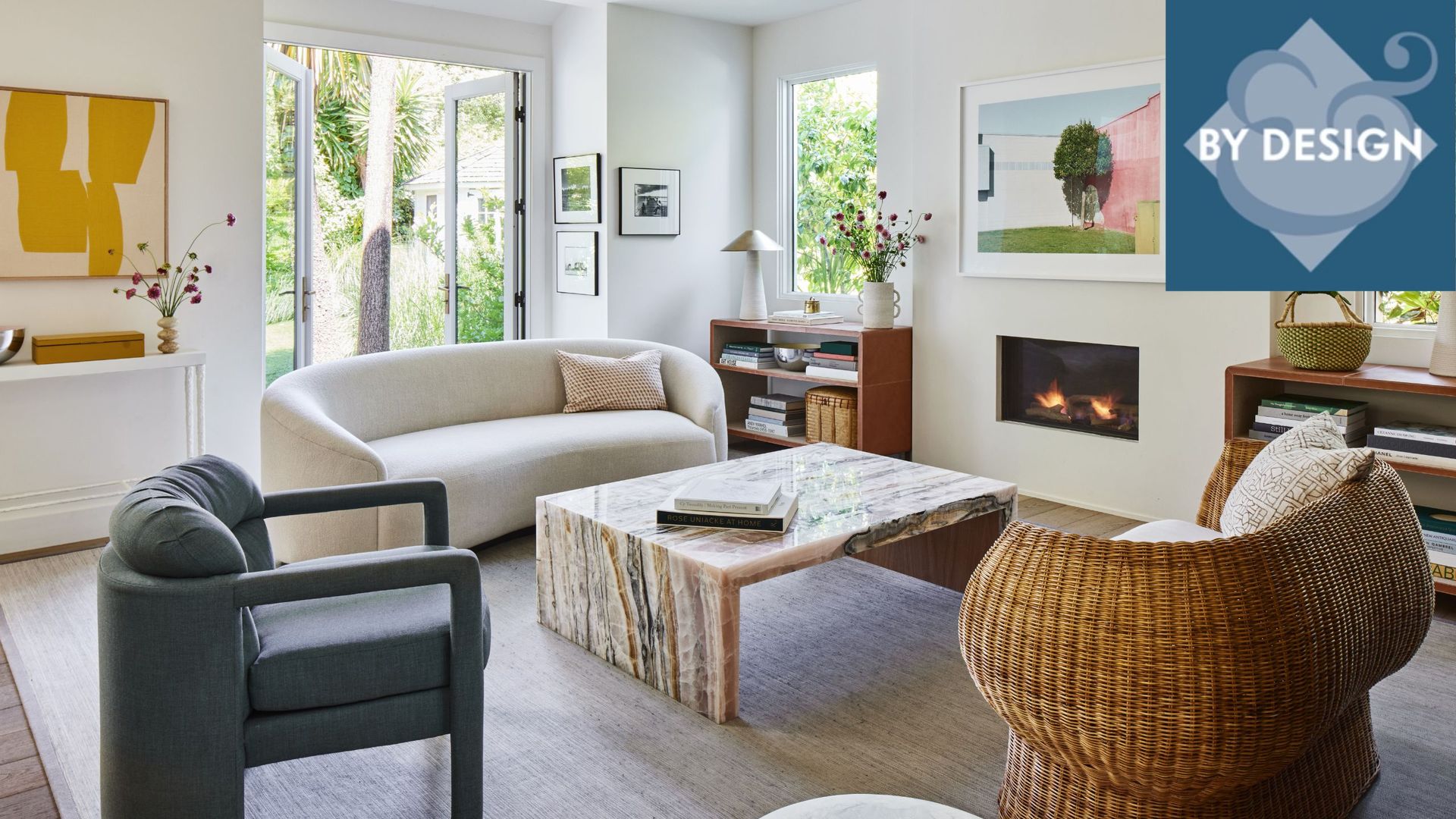Cozy modern living room with a mix of sofa and chair seating, beige rug on wooden floor, modern fireplace to the left, with artwork an shelving surrounding