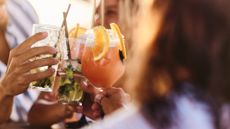 Close up of unrecognizable friends toasting with cocktails in a bar.