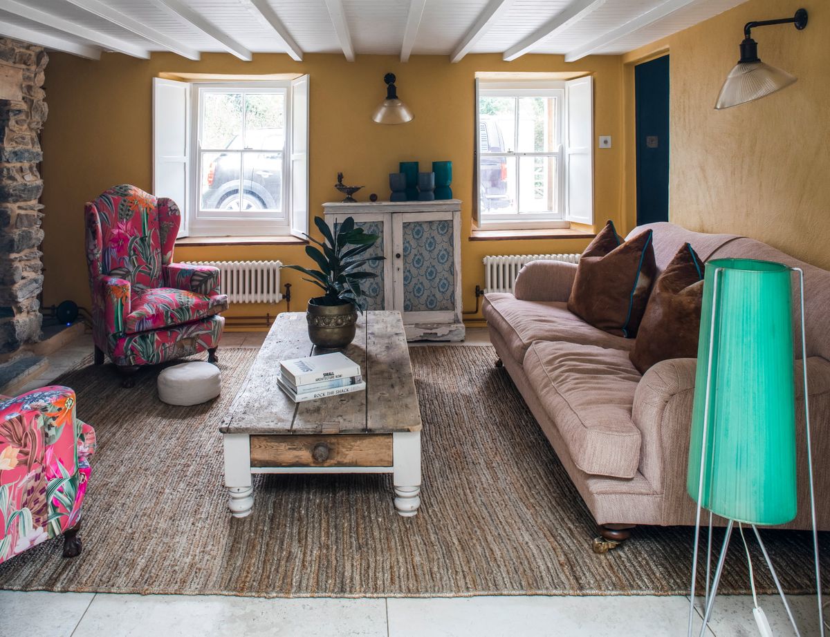 A living room with yellow walls an white beams, with a brick fireplace