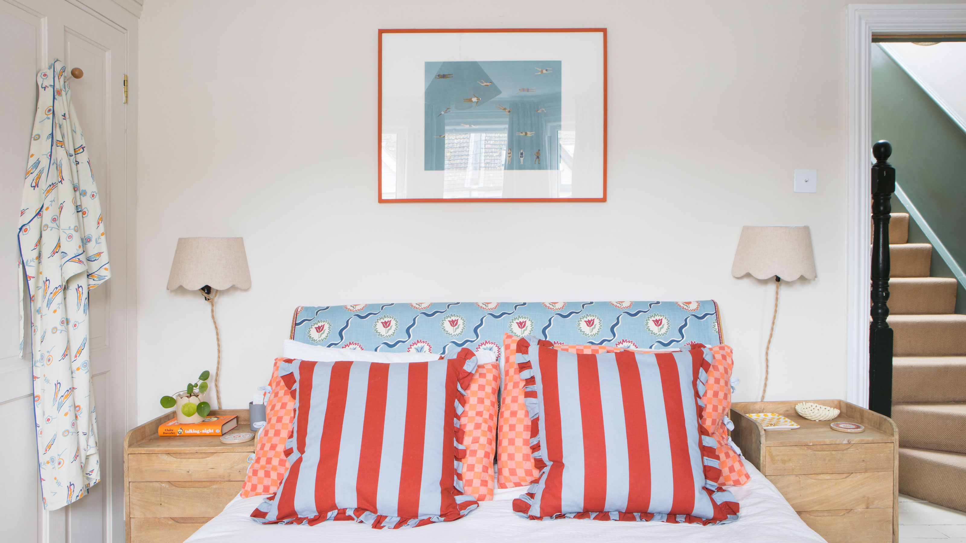 White bedroom with blue headboard and white wall lights and wooden side tables