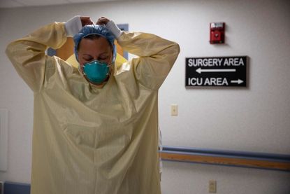 A health care worker puts on PPE.