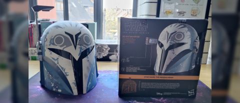 Bo-Katan helmet next to the cube-shaped box it comes in. Image in 21 by 9 format.