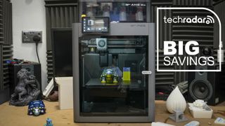 A Bambu Lab P2S in our workshop, with a blue diamond TechRadar badge reading 'Big Savings'