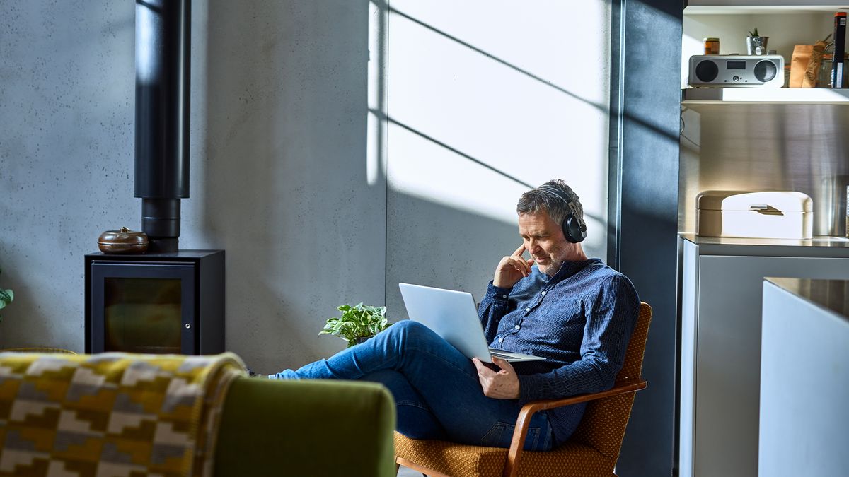 Man using work laptop while sitting on a couch at home.