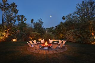 White chairs surround a fire pit under a bright moon at the Parker Palm Springs