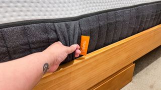 A hand pulling on a handle of the Emma Luxe mattress