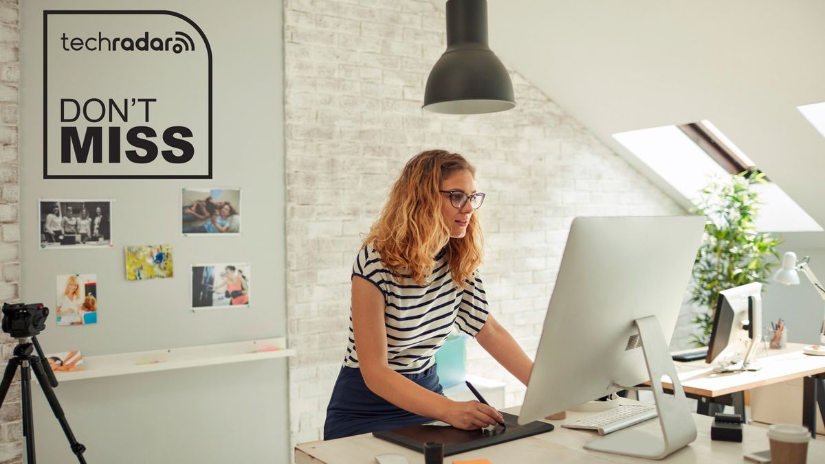 Woman standing at a desktop computer and drawing on a tablet in a loft-style space. The TechRadar logo and &quot;Don&#039;t Miss&quot; text are in the top left in black.