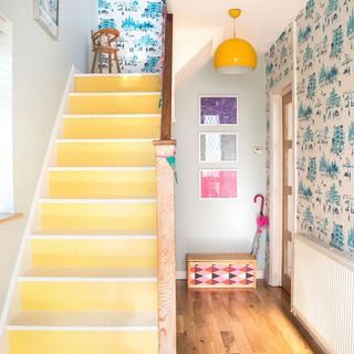 yellow staircase with wallpaper and hanging light