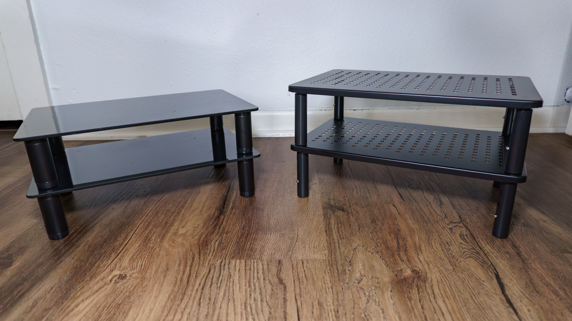 A set of glass and a set of metal monitor stand on the floor
