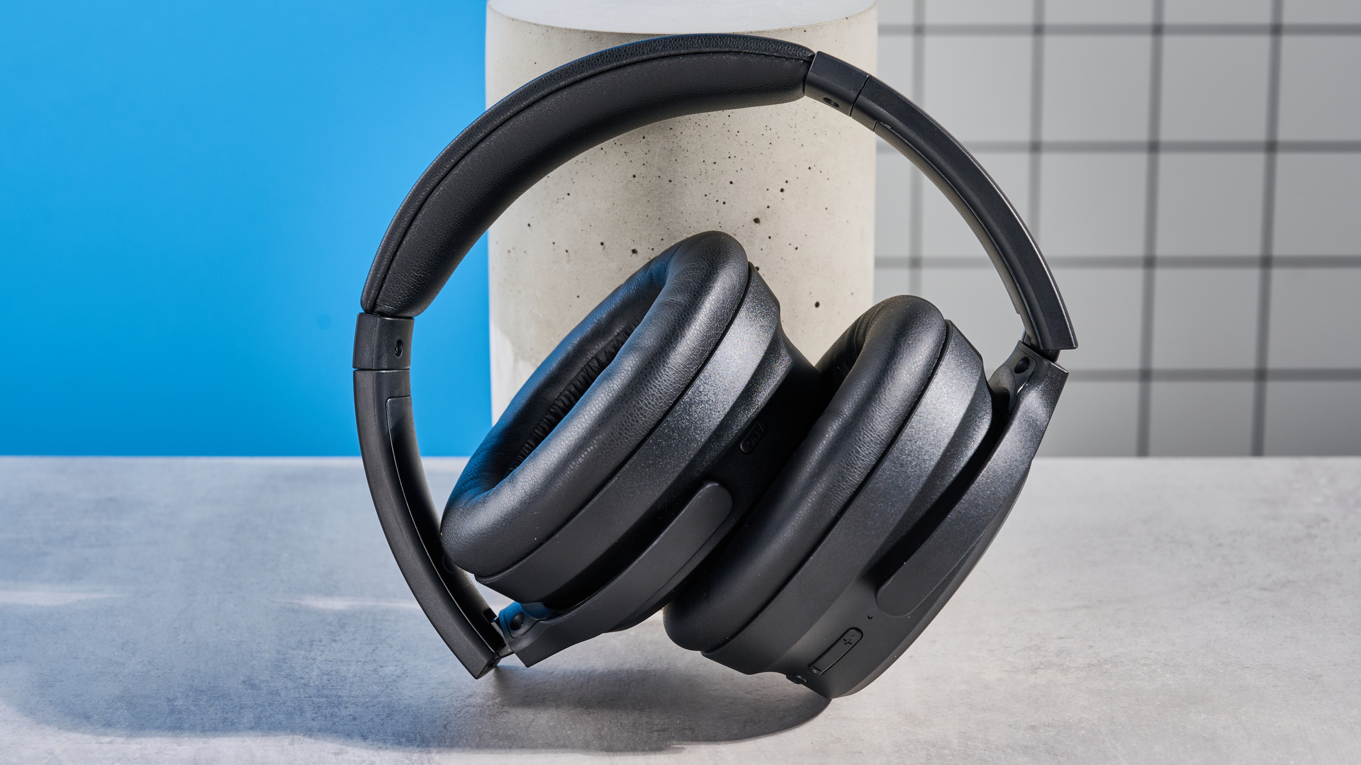 the earfun tune pro headphones, in black, with soft pleather cups, and gray cups, photographed against a blue background