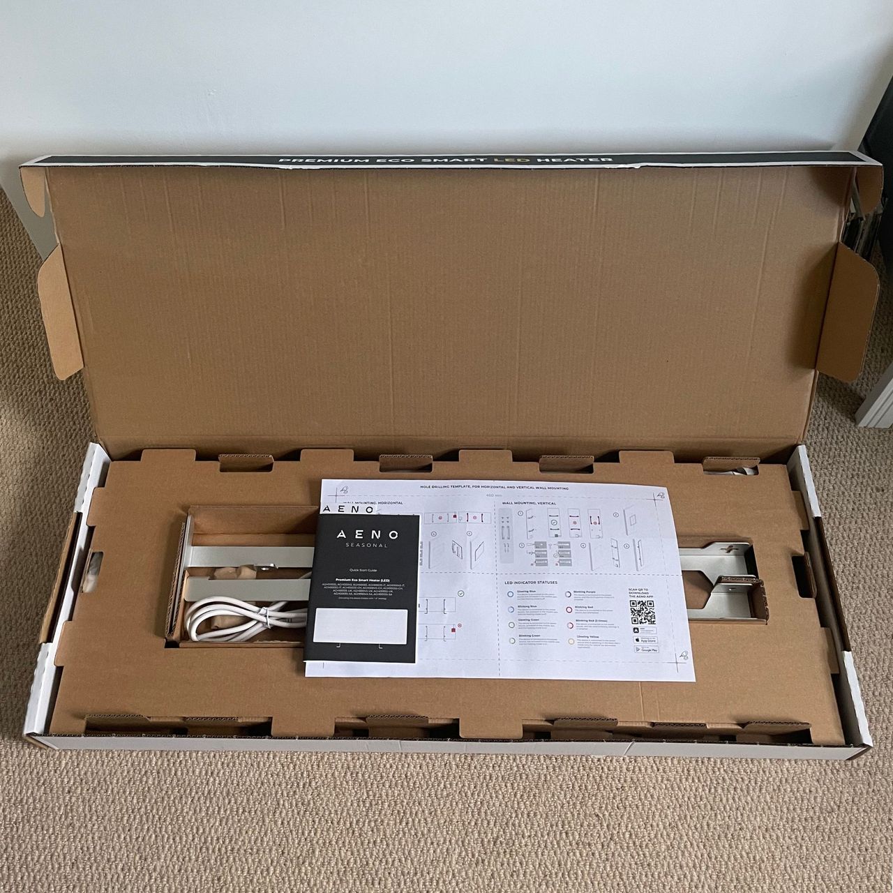 An open box of the Aeno Premium Eco Smart Heater, revealing the contents inside