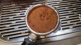 A sprinkle of coffee grounds on the top of a coffee puck