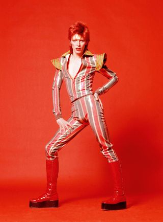 Portrait of David Bowie in 1973 wearing bright striped outfit.