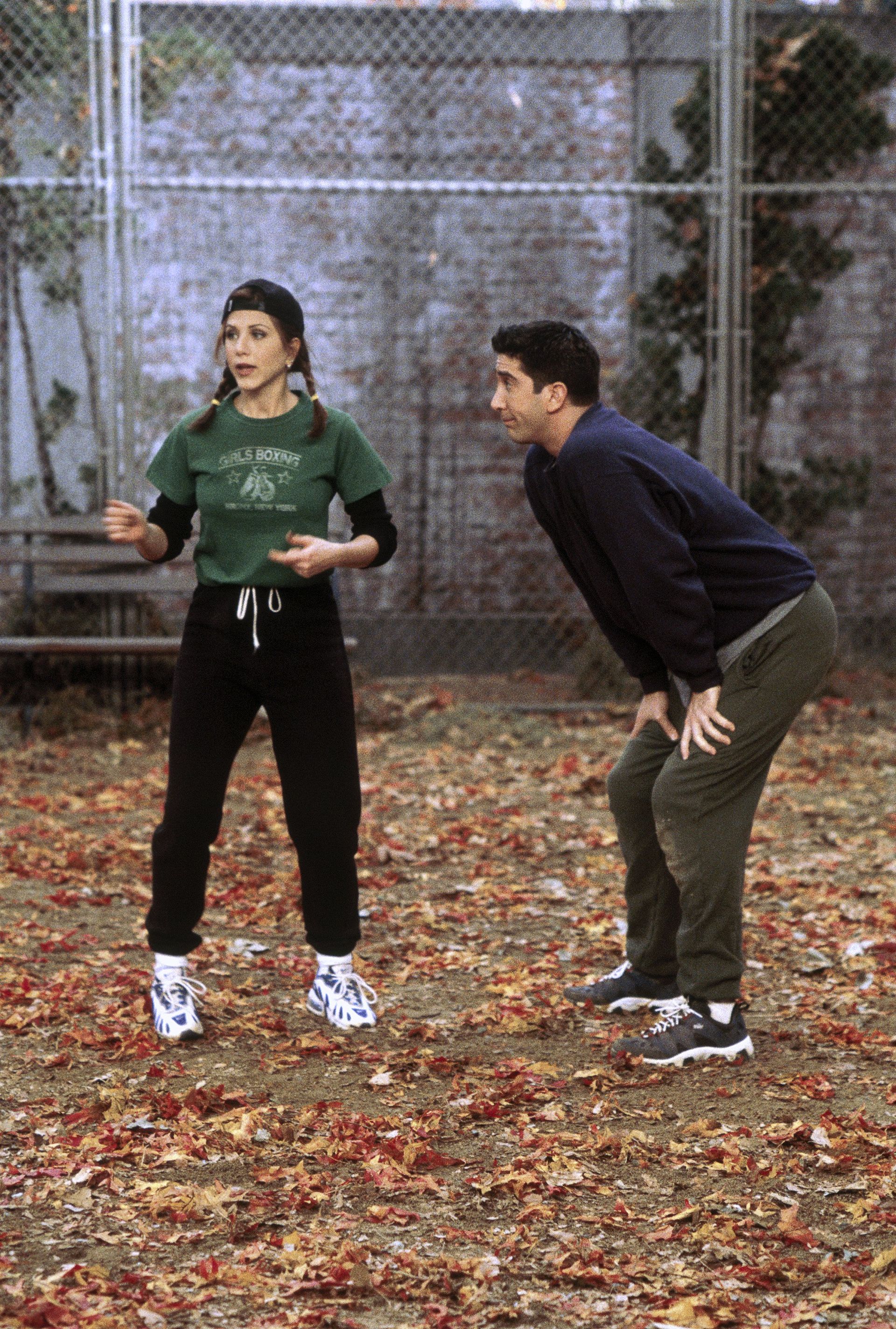 Jennifer Aniston as Rachel Green wears the layered t-shirt trend in friends in the 90's. She wears a green graphic cropped tee. A black long sleeve, black tracksuit bottoms and a nike trainer. This mage was taken from Getty.