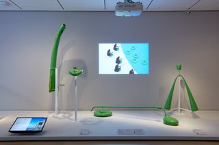 Green tubular objects on display in front of a TV screen with animation