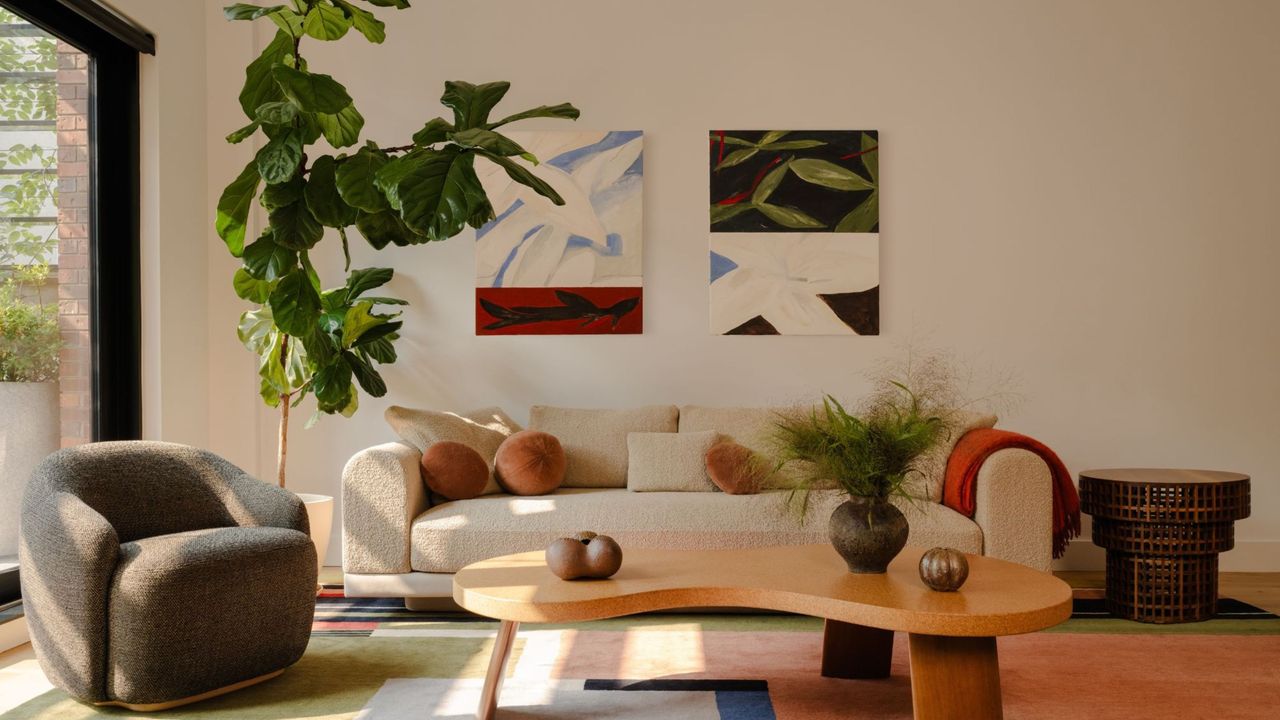 A living room with cream walls, a beige sofa, and an olive toned armchair 