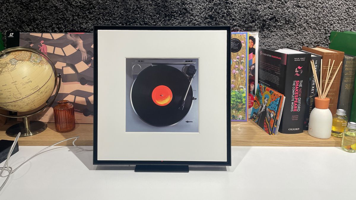 Samsung Music Frame wireless speaker on busy shelf with picture of turntable and record in frame