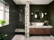 A khaki green bathroom with a large focus on terrazzo, some dark wood and brass fittings