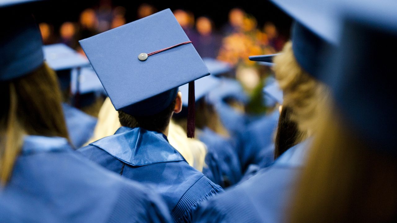 Graduates in blue graduation gowns and mortar boards at their graduation ceremony.