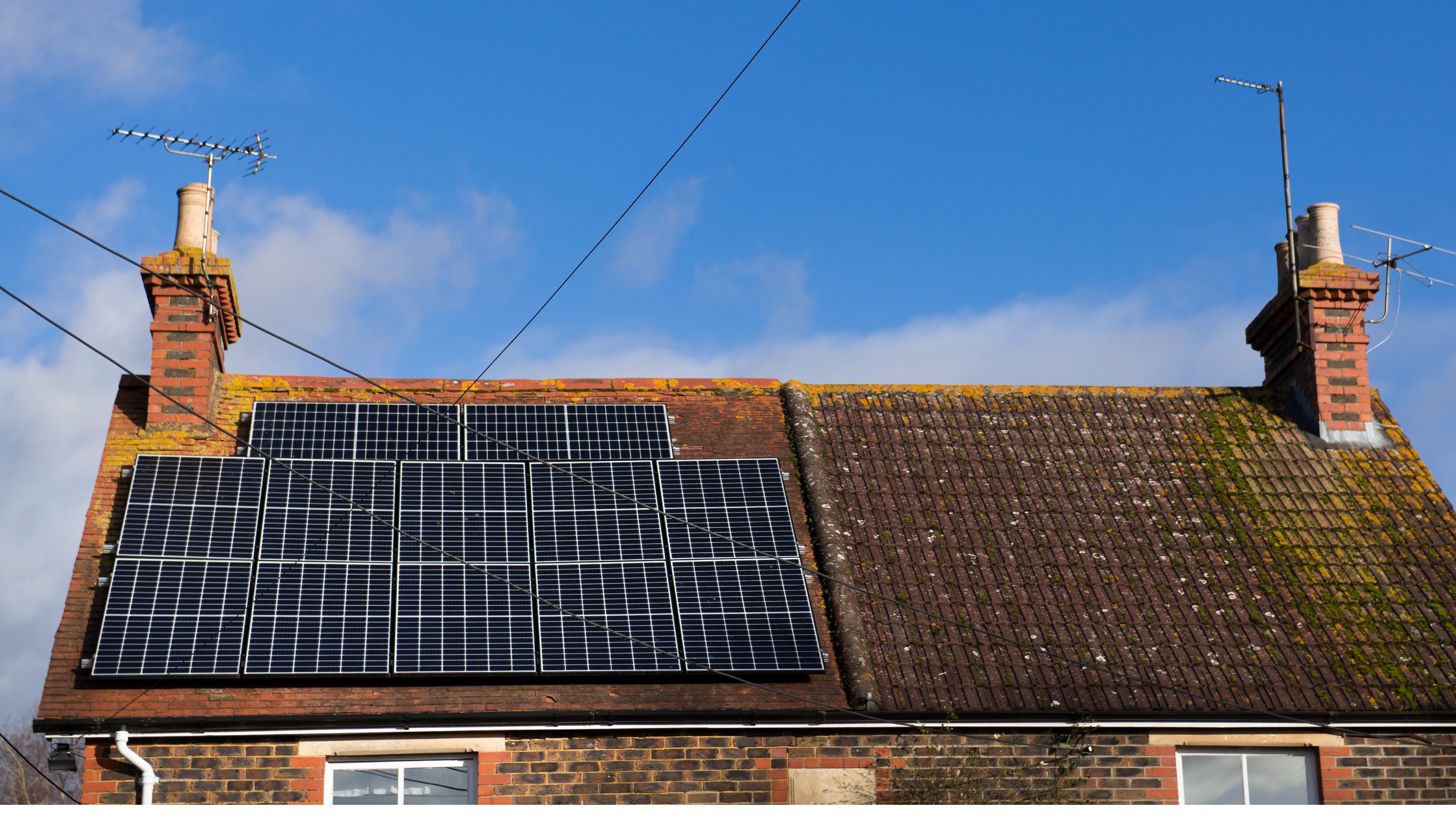Solar panels on the pitched roof of a brick semi-detached cottage
