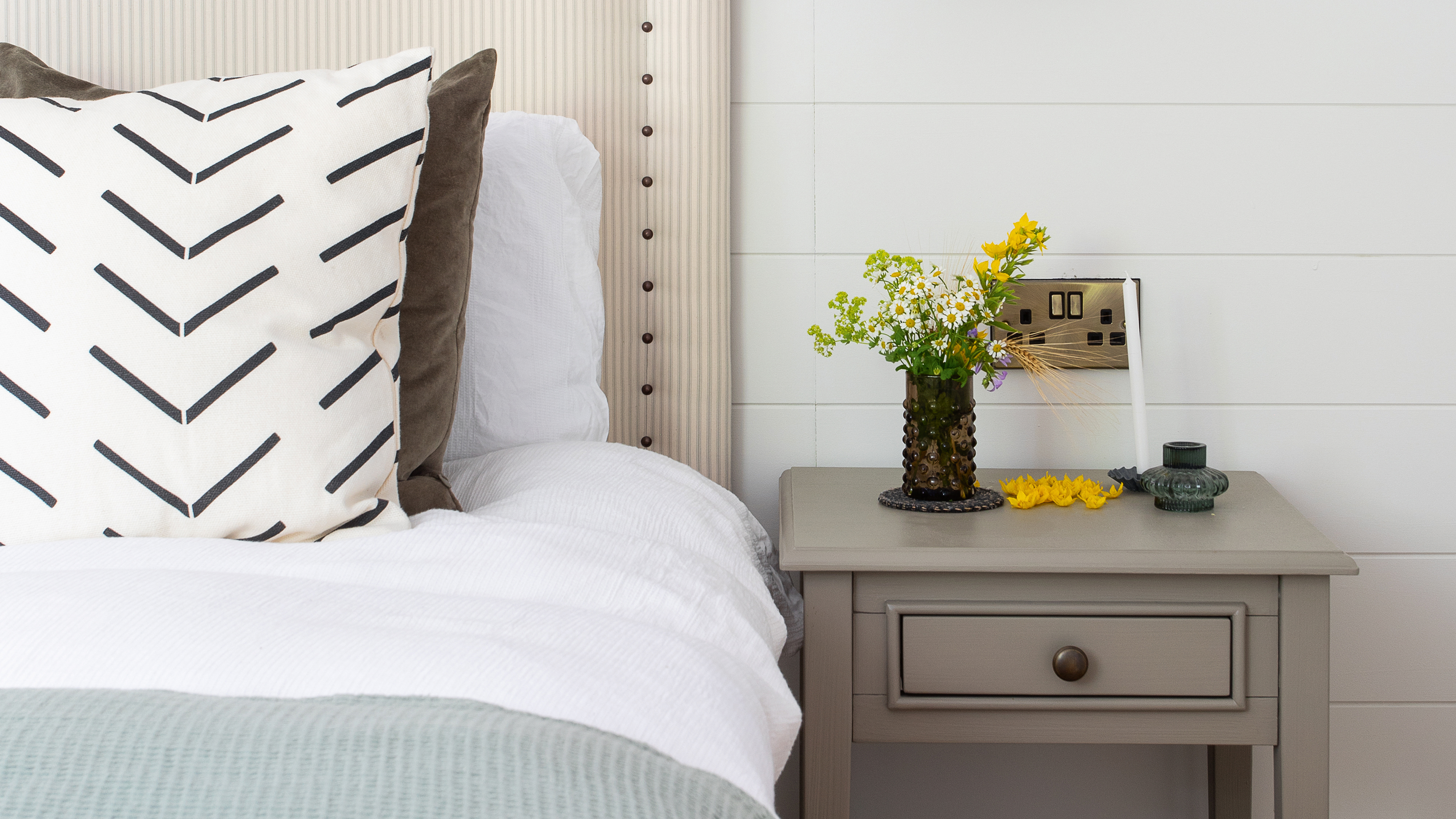 A bed with a grey bedside table next to it