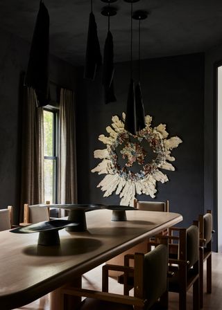 A dining room with wooden dining furniture, color drenched in black