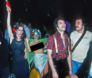 Freddie Mercury at the launch party, next to a half-naked girl