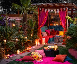 A selection of bold outdoor furnishings in bright pinks, orange, deep blues. With outdoor stake lights and lanterns and an adorned wooden pergola