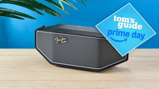 The Fender x Teufel Rockster Cross on a wooden table with a blue background and a blue Tom's Guide Prime Day deal badge in the top right corner of the image.