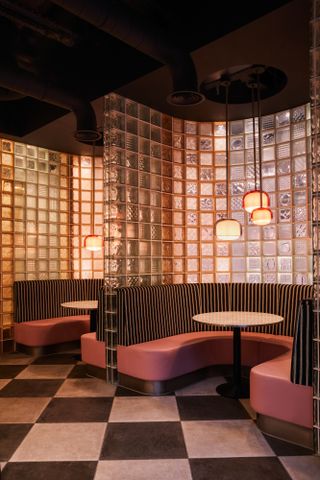 two curved booths with pink seats are enclosed in glass block walls.