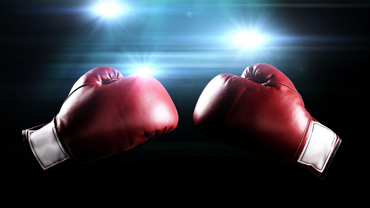 A pair of red boxing gloves against a black background with flashing lights.