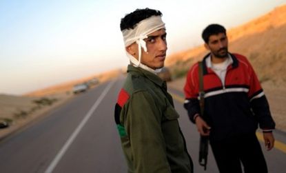A wounded rebel walks a desolate road in eastern Libya: Despite the backing of the West, anti-Gadhafi forces are on the defensive, and struggling economically and militarily.