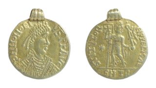 A golden pendant resembling a coin with an emperor on it