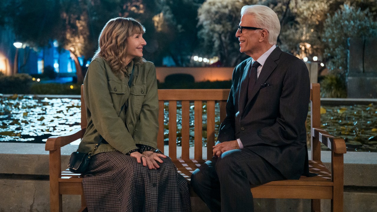 From left to right: Mary Steenburgen and Ted Danson sitting next to each other on a bench, smiling.
