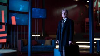 Christoph Waltz as Regus Patoff standing in a suit looking off camera.