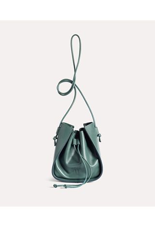 A geometrically cut, dark green handbag stands against a white background.