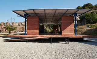 Steel framed building with wooden deck and walls and metal roof on a gravel plot