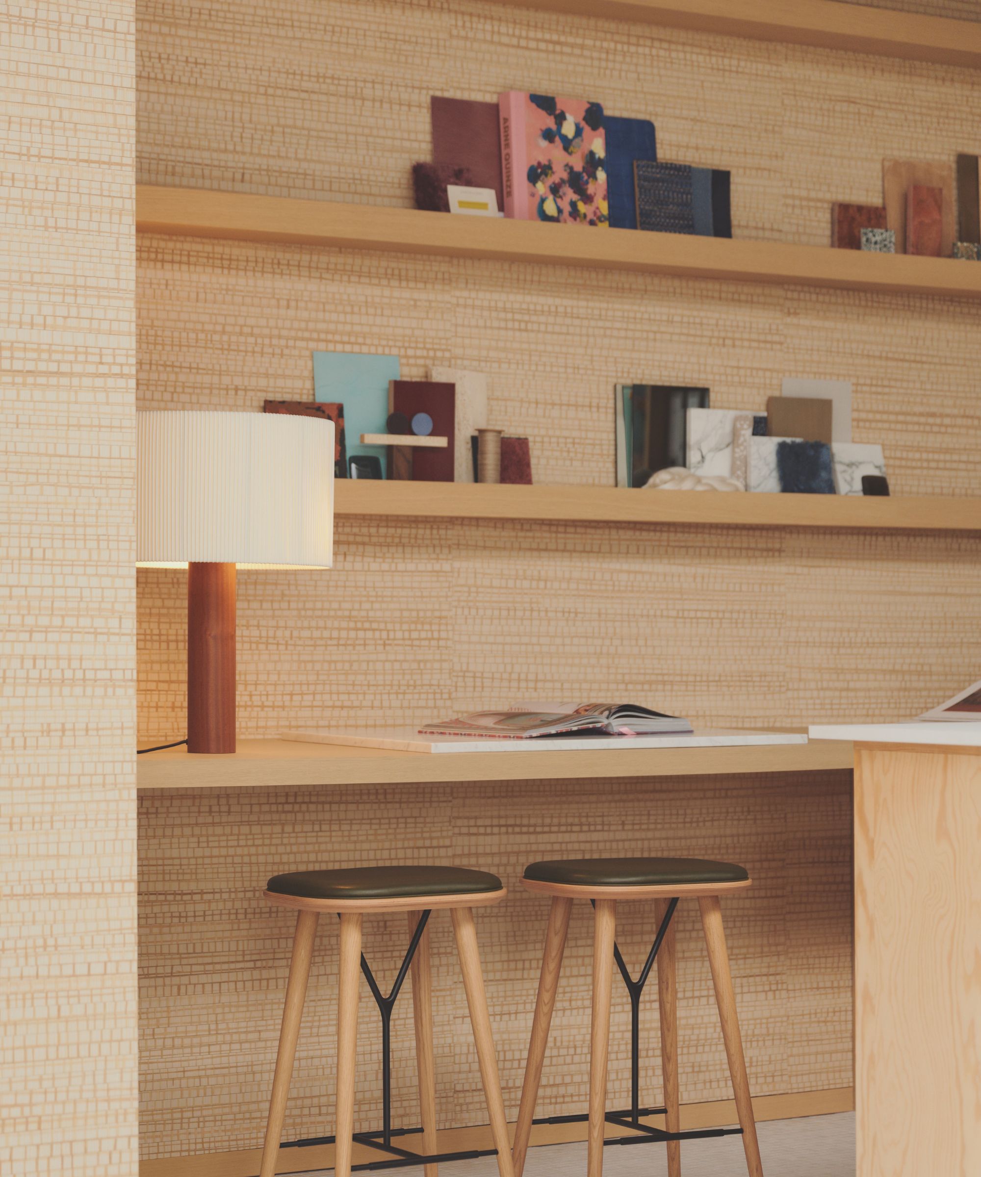 A wall with shelving, two wooden stalls with buttery leather seats in dark olive green and a modern lamp
