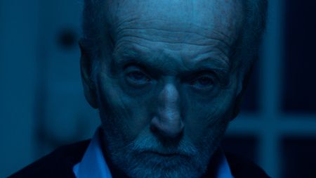 A close-up of a sinisterly glowering John Kramer.