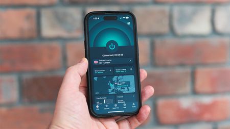 Hand holding an iPhone with the ExpressVPN app open on its home page and in dark mode 