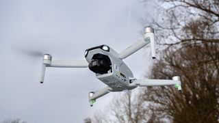 Ruko F11PRO 2 drone flying in front of trees and a grey cloudy sky