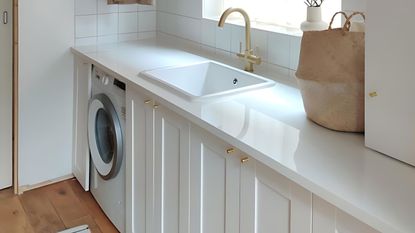 White bathroom laundry room combo with brass sink