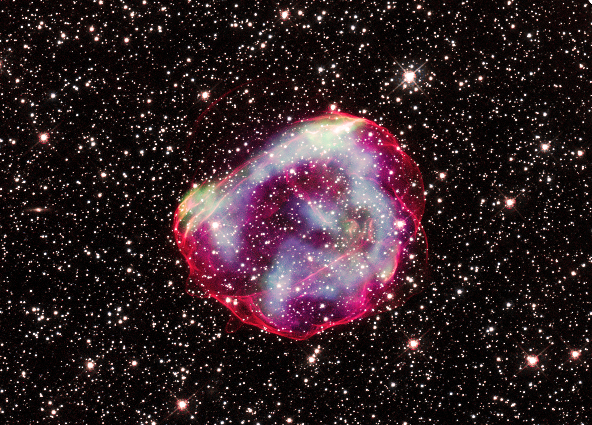 A glowing globular structure of red and blue gas against a backdrop of stars.
