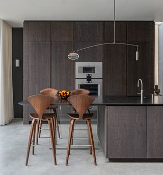 a modern dark wood kitchen with stools over a cantilevered island