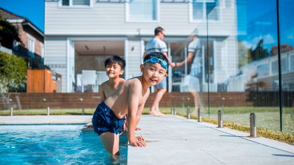A family with young kids plays at a pool.