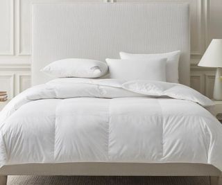 Sferra Somerset Duvet Comforter on a white bed frame against white walls.